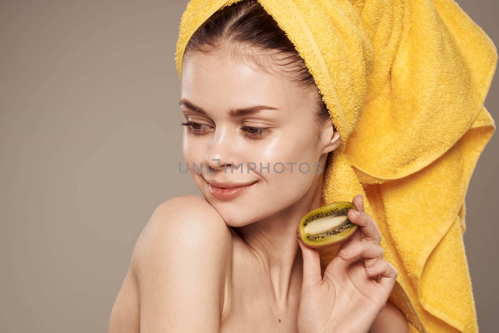 cheerful woman with a towel on her head and hands skin care naked shoulders beige background. High quality photo