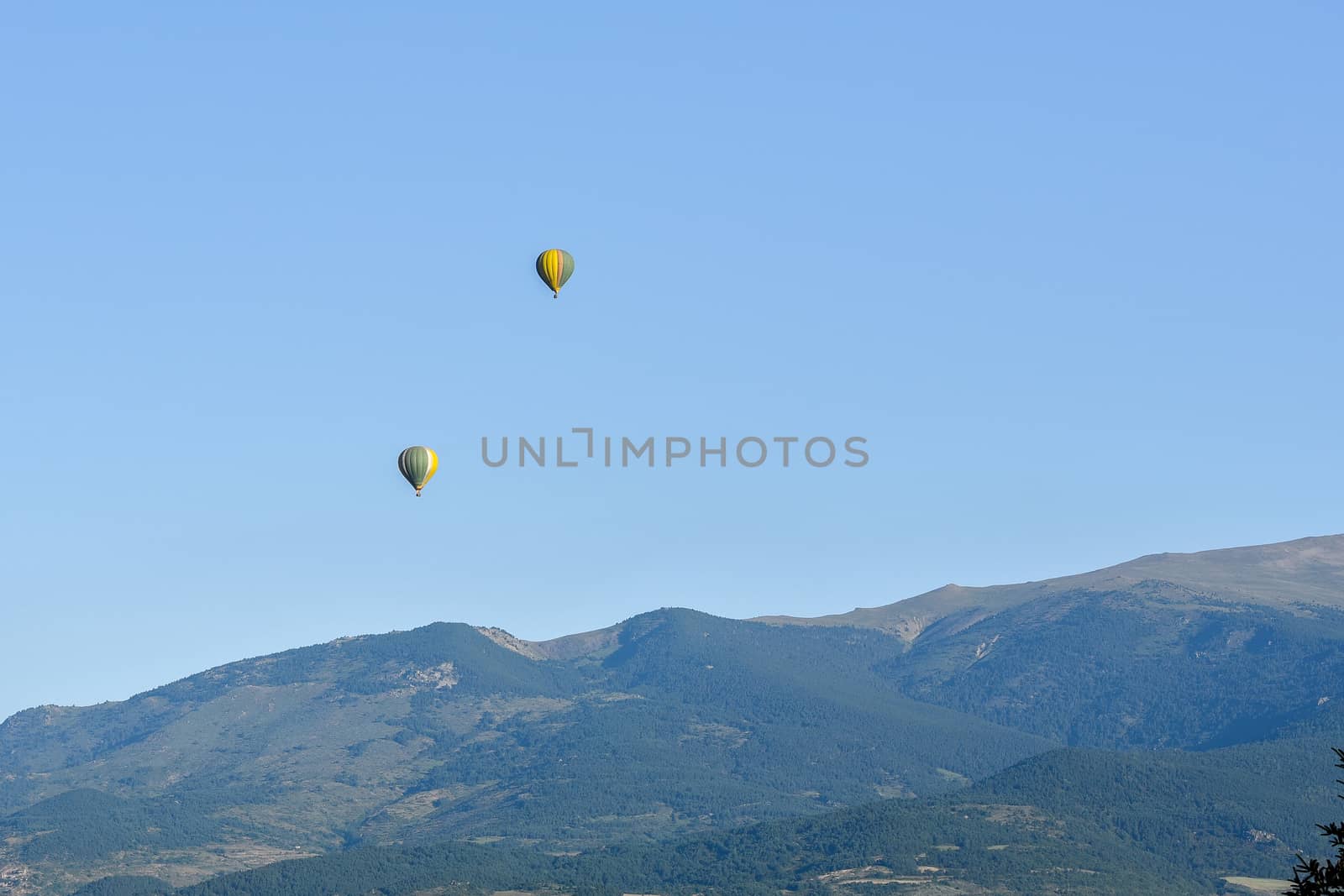 Colorful hot air balloons flying over the mountain in Puig Cerda, Spain.