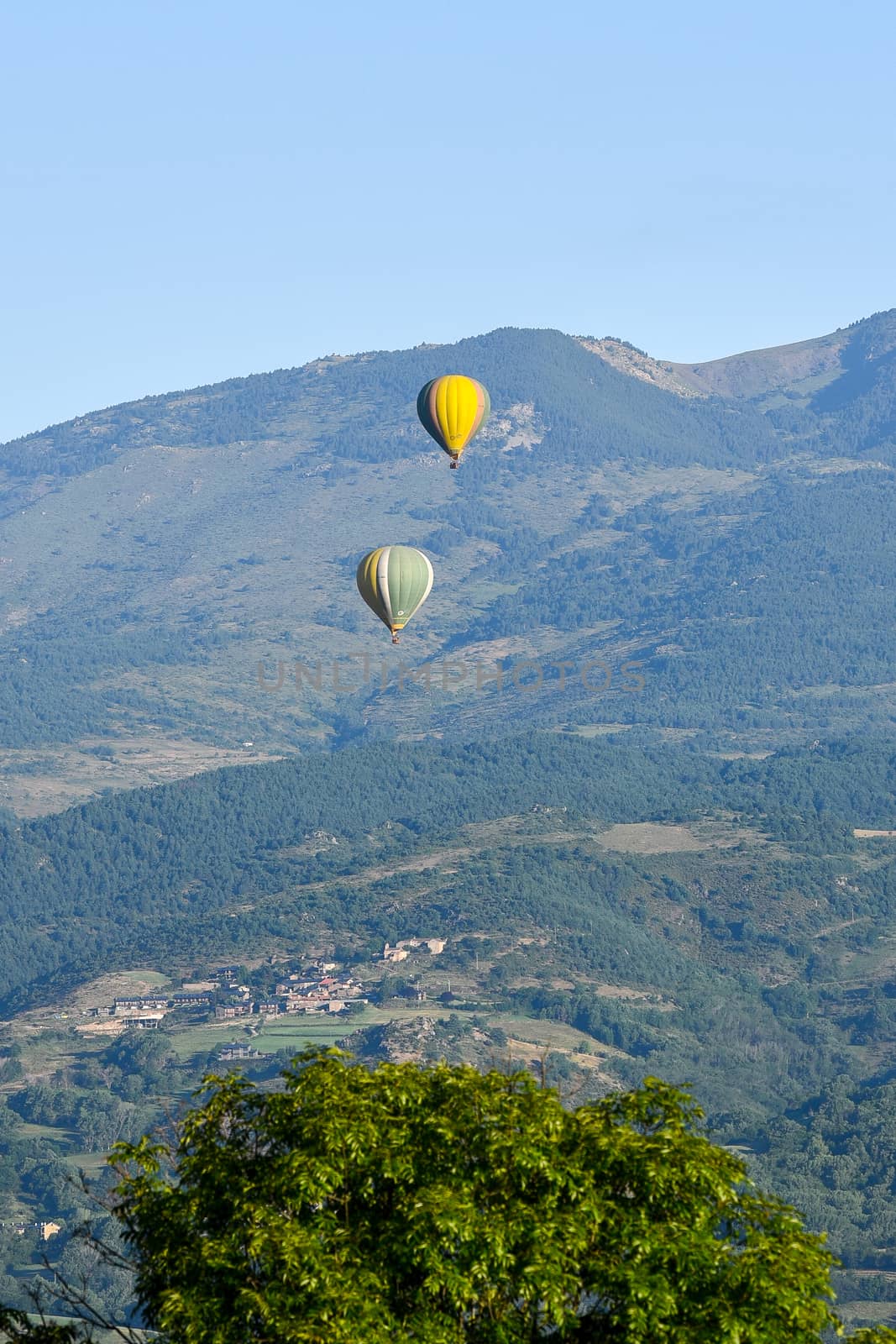 Colorful hot air balloons flying over the mountain in Puig Cerda, Spain.