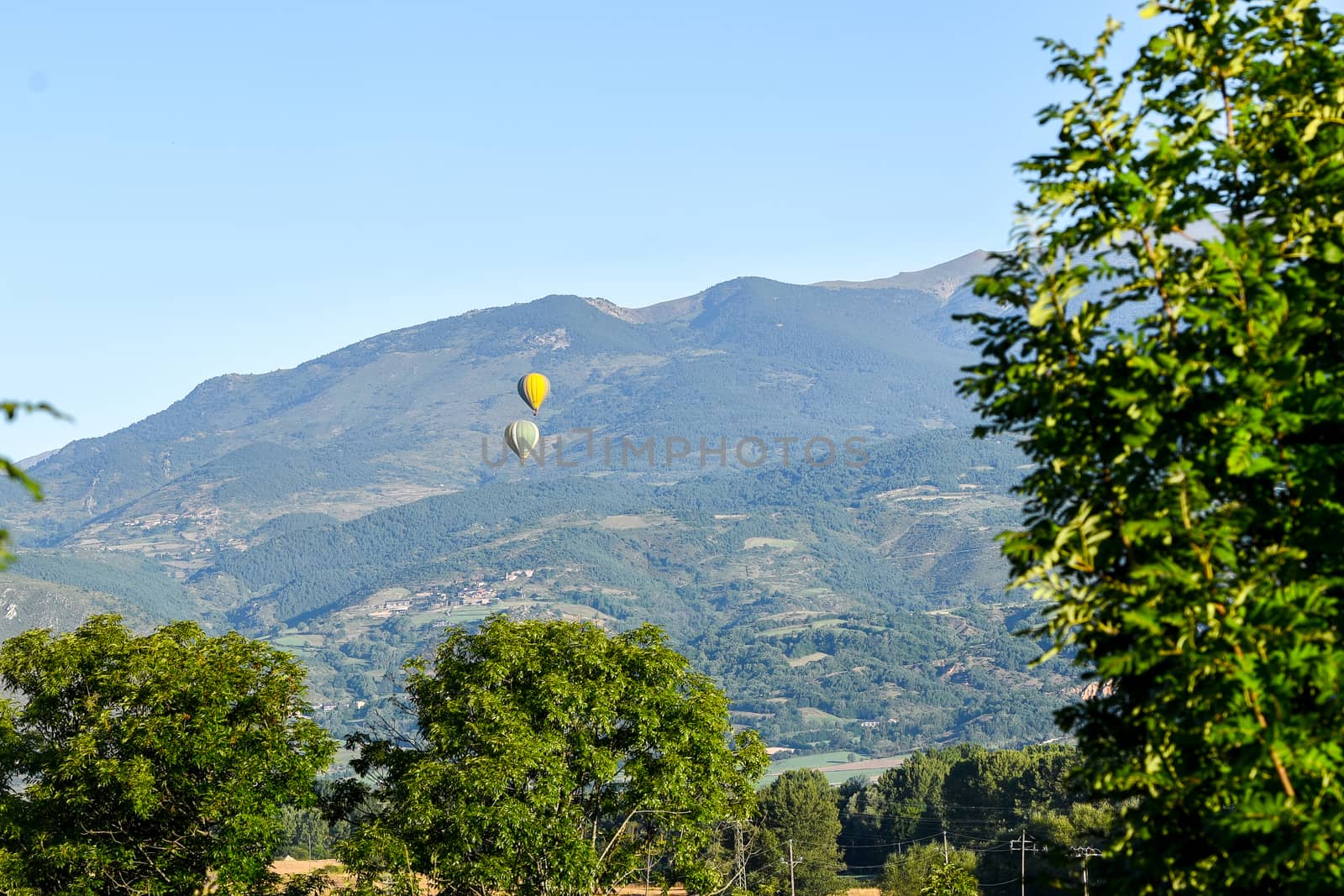 Colorful hot air balloons flying over the mountain in Puig Cerda, Spain.