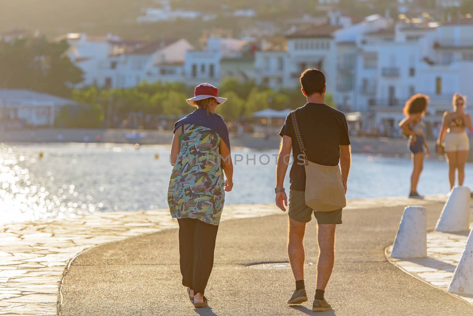 People in the beach and houses of the village of Cadaques, Spain by martinscphoto