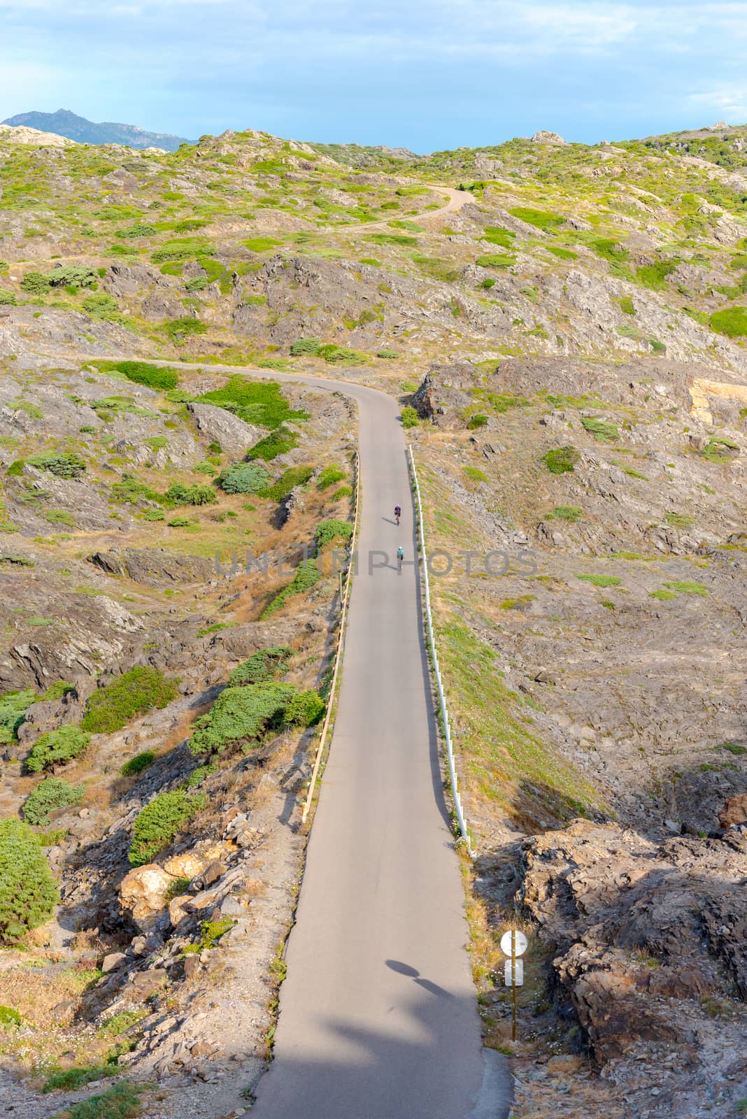 Parc Natural Cap de Creus, Spain :  8 july 2020 : Two cyclists in  Cap de Creus, natural park. Eastern point of Spain, Girona province, Catalonia. Famous tourist destination in Costa Brava. Sunny summer day with blue sky and clouds