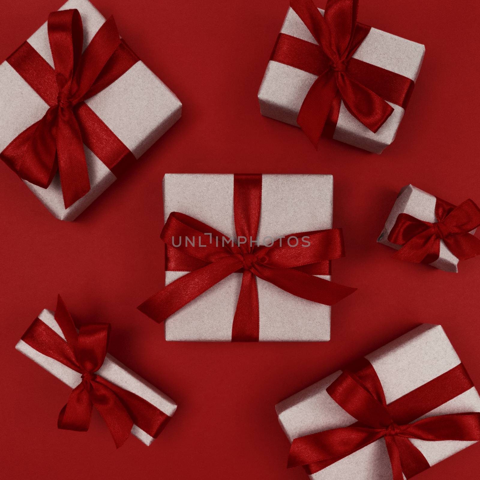 Gift boxes wrapped in craft paper with a red ribbons and bows. Festive monochrome flat lay.