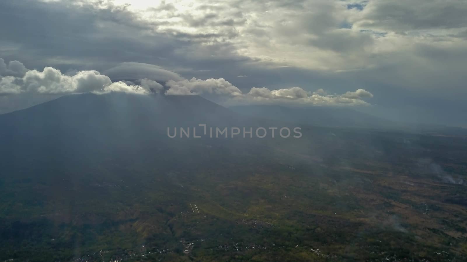 volcano with cloudy clear sky. Mount Merapi in Indonesia. Cloudy sky with a volcano in the background. Clouds around the top of the mountain. The sun's rays shine through the clouds.