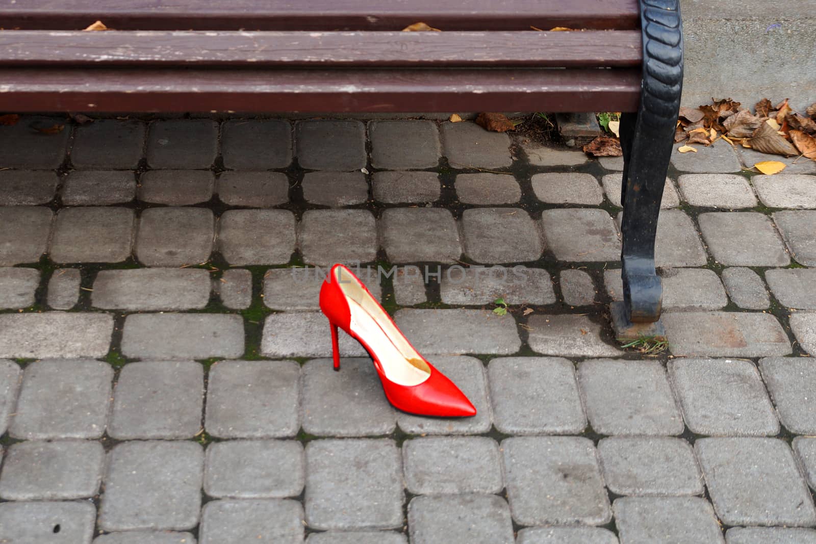 a red women's shoes lies near an empty bench