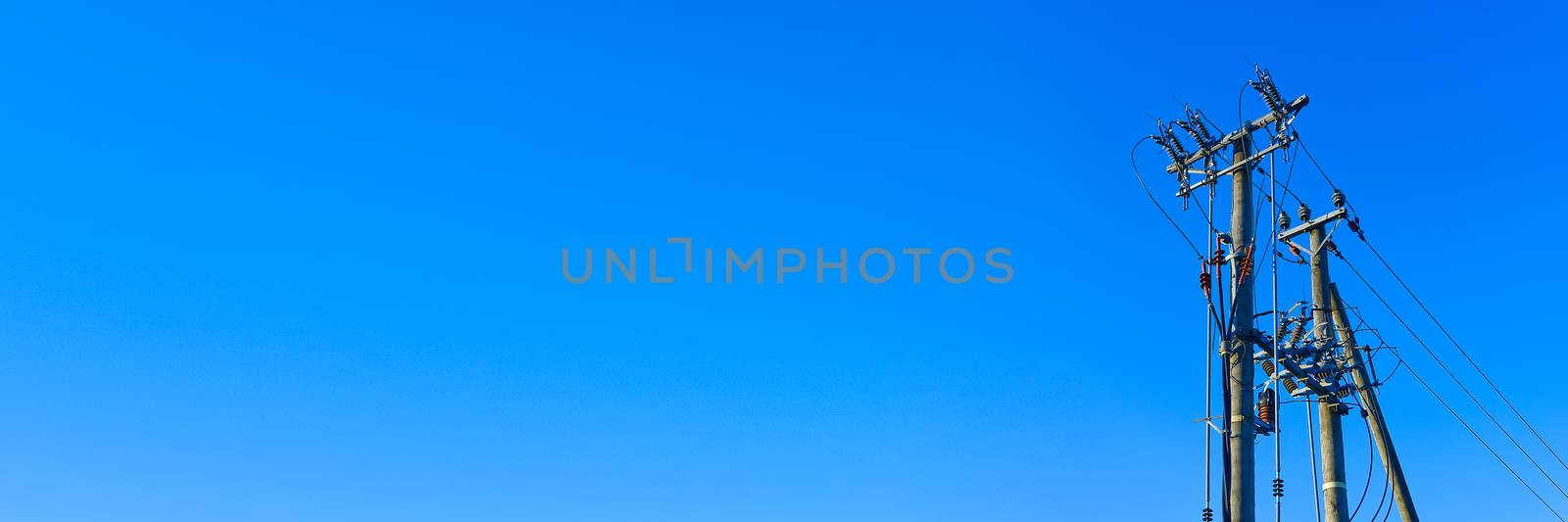 electric power sky lines and connections on a wooden post. wooden electricity post against blue sky. Electric power lines and wires with blue sky. by PhotoTime