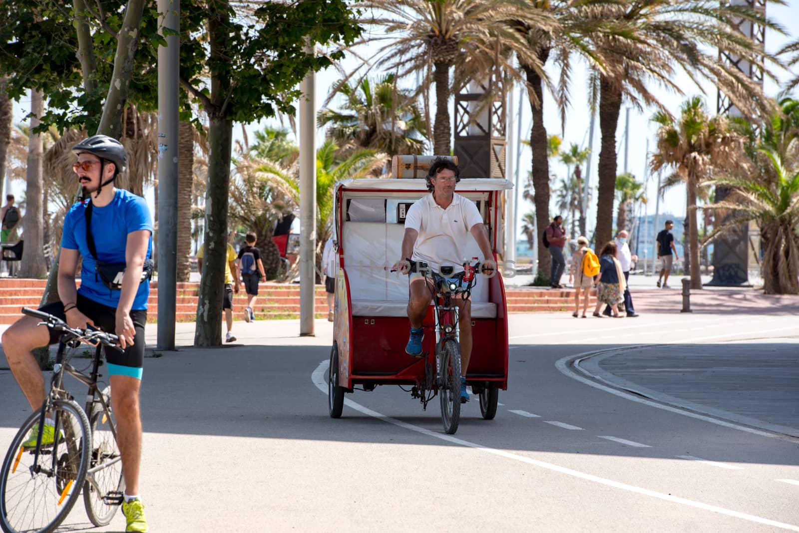 BARCELONA - JUNE 26, 2020: tuk tuk in Barceloneta beach with people in summer after COVID 19 on June 26, 2020 in Barcelona, ​​Spain.