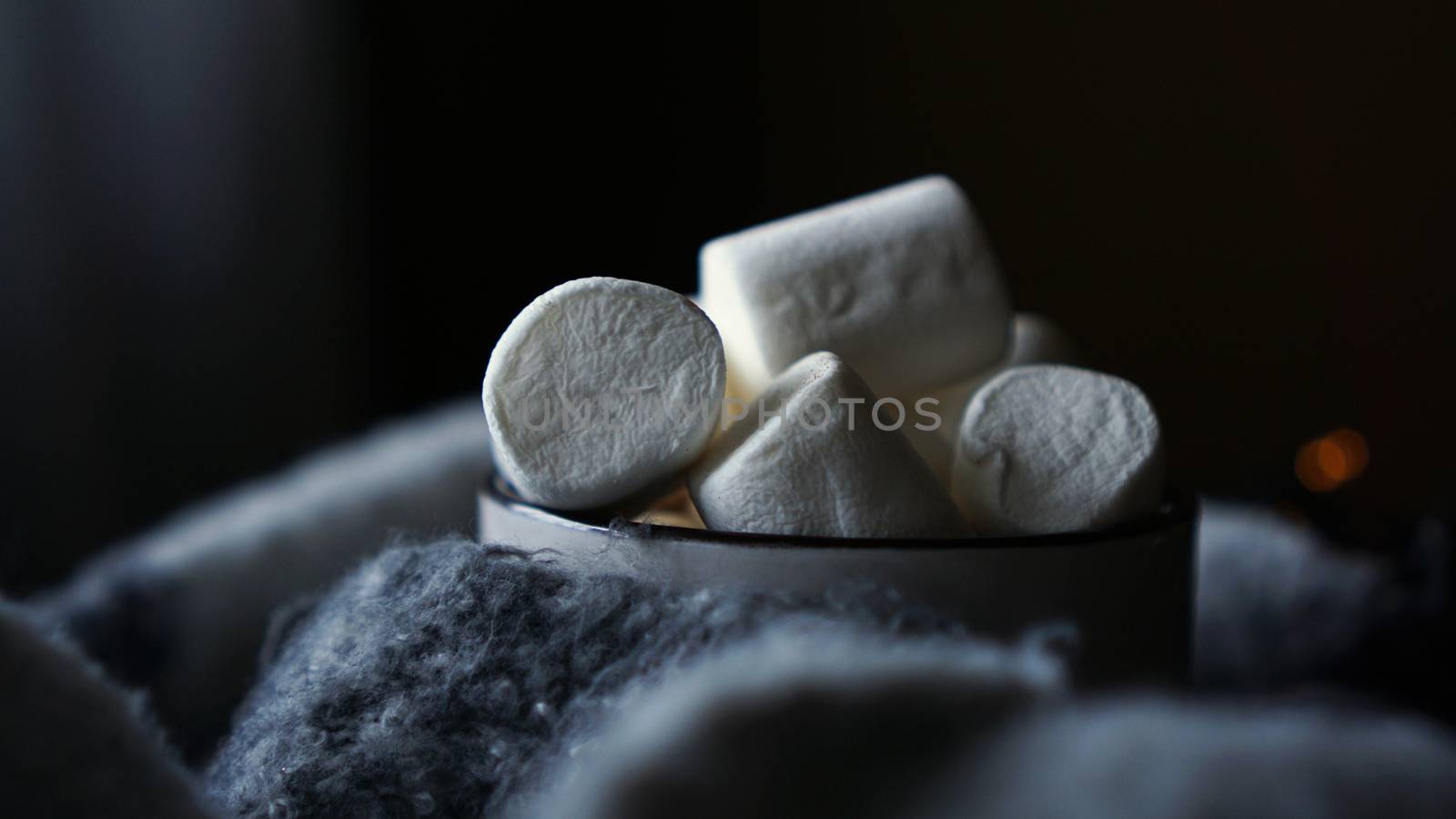 Hot cocoa with marshmallow in a white ceramic mug. The concept of cosy holidays and New Year. Dark background - closeup photo