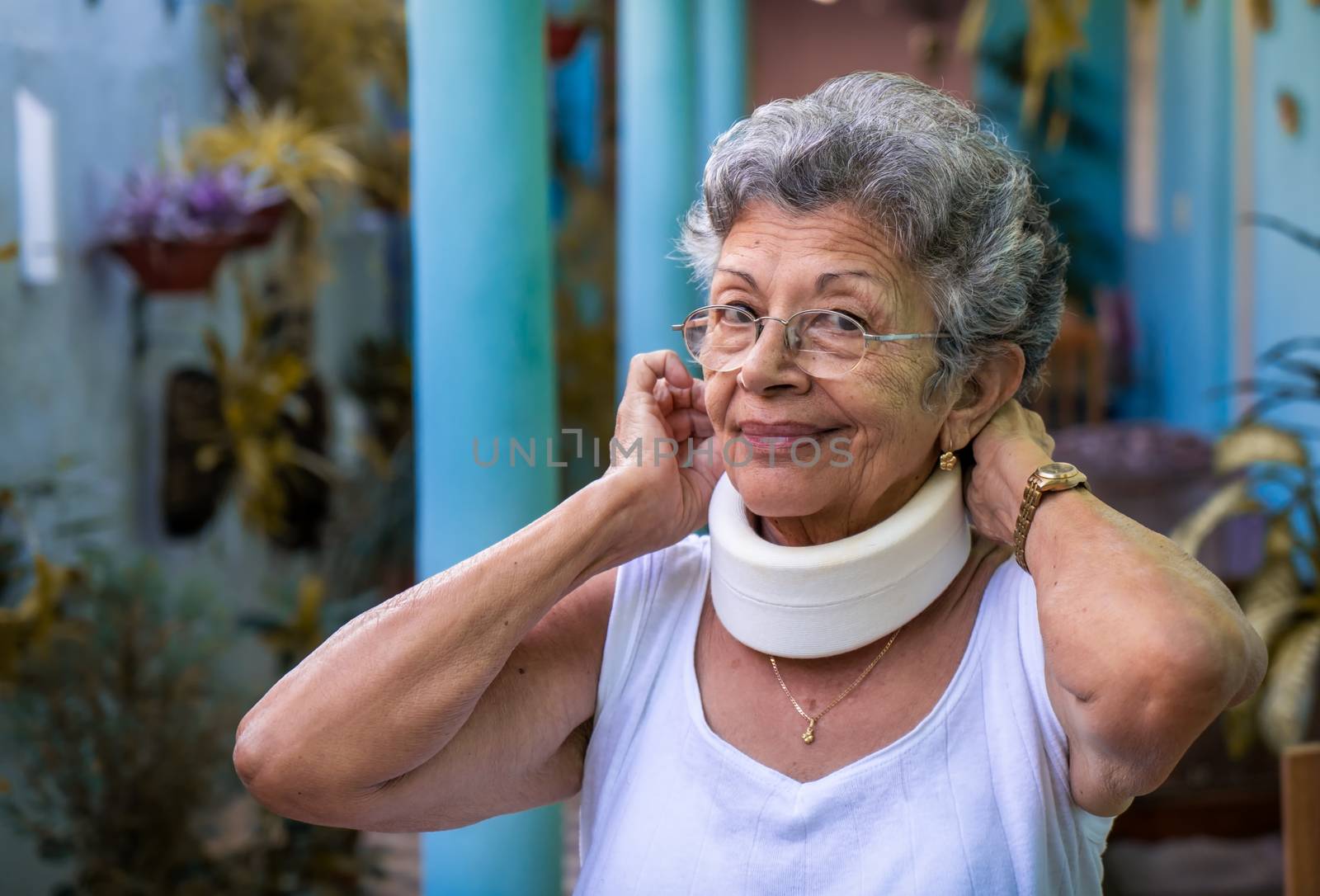 Smiling elderly woman putting on homemade looking cervical immobilizer collar