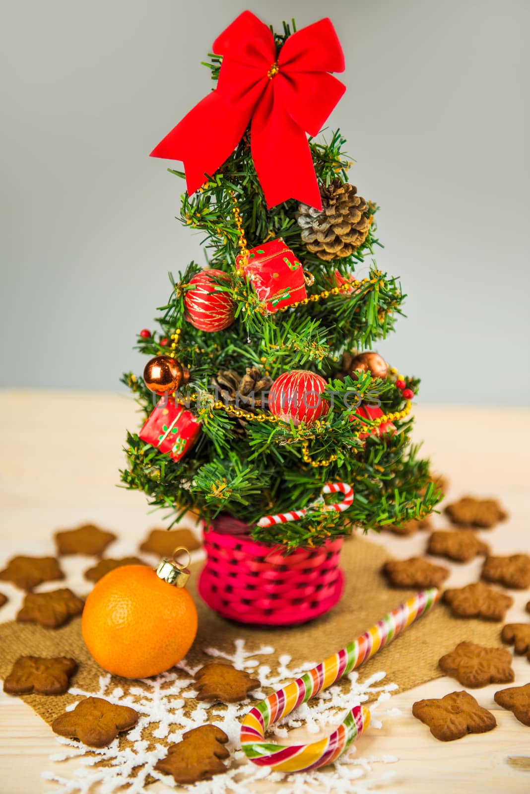 Decorated Small Christmas tree isolated with gingerbread cookies and sweets on a wooden background