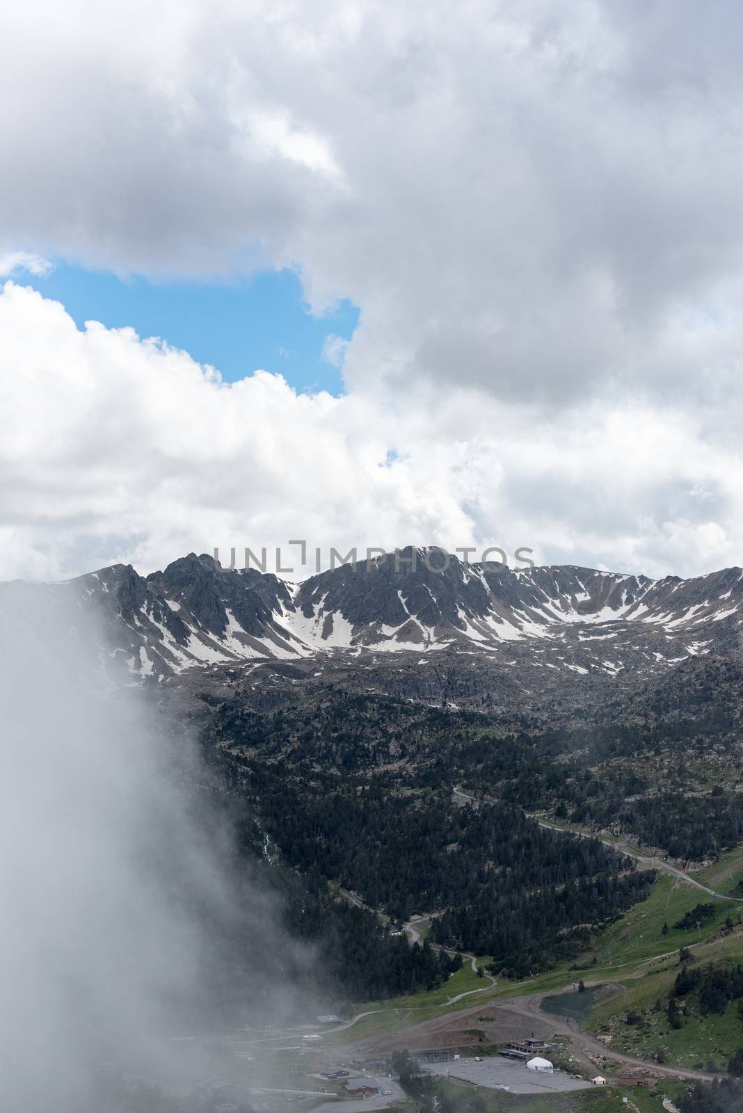 Sunny day with low clouds in the town of Pas de la Casa on the border between France and Andorra in June 2020.