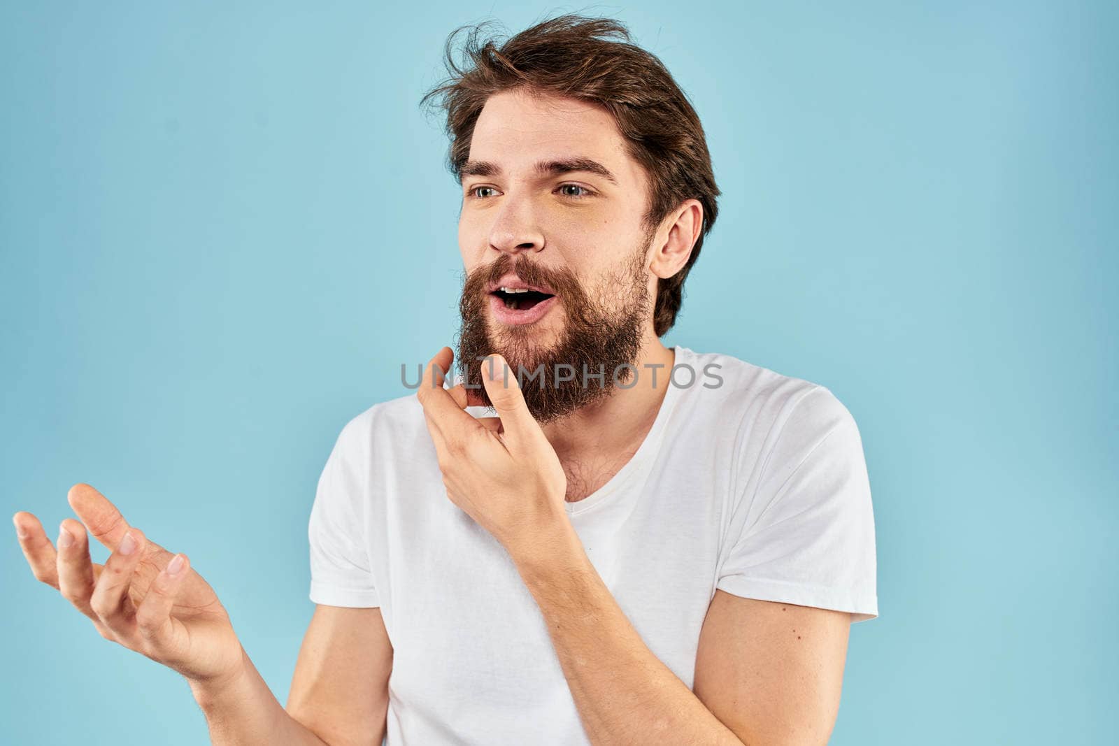 Emotional man with a beard in a white t-shirt blue background fun lifestyle. High quality photo