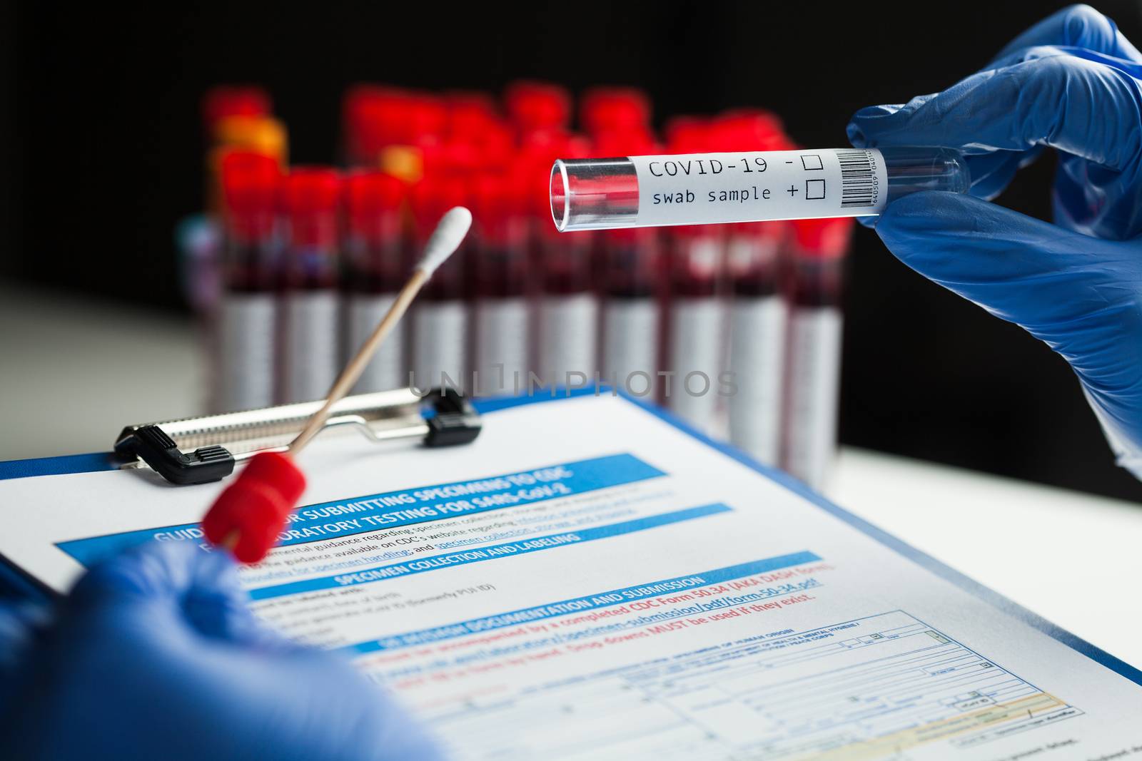 rt-PCR COVID-19 virus disease diagnostic test,lab technician wearing blue protective gloves holding test tube with swabbing stick,swab sample equipment kit & CDC form specimen submitting guidelines