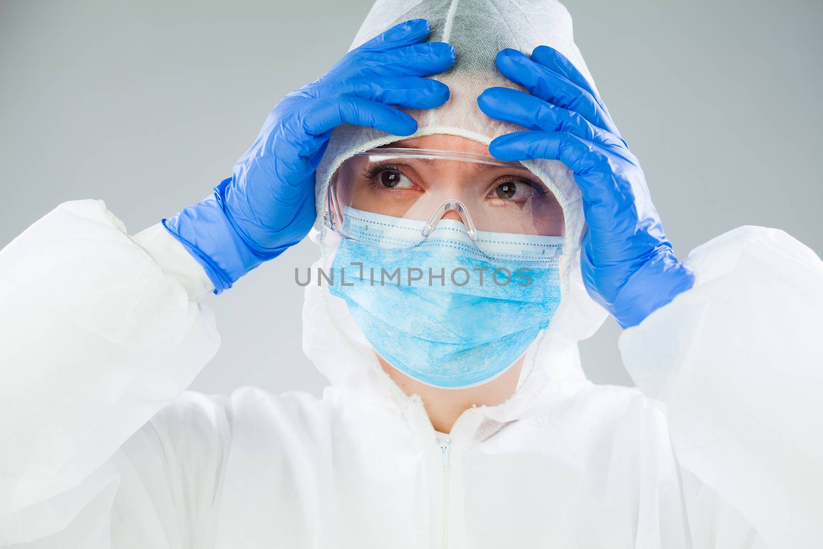 Desperate medical NHS EMS worker in white protective suit,blue surgical mask latex gloves & safety goggles,Coronavirus COVID-19 pandemic crisis causing shortage of protective personal equipment supply