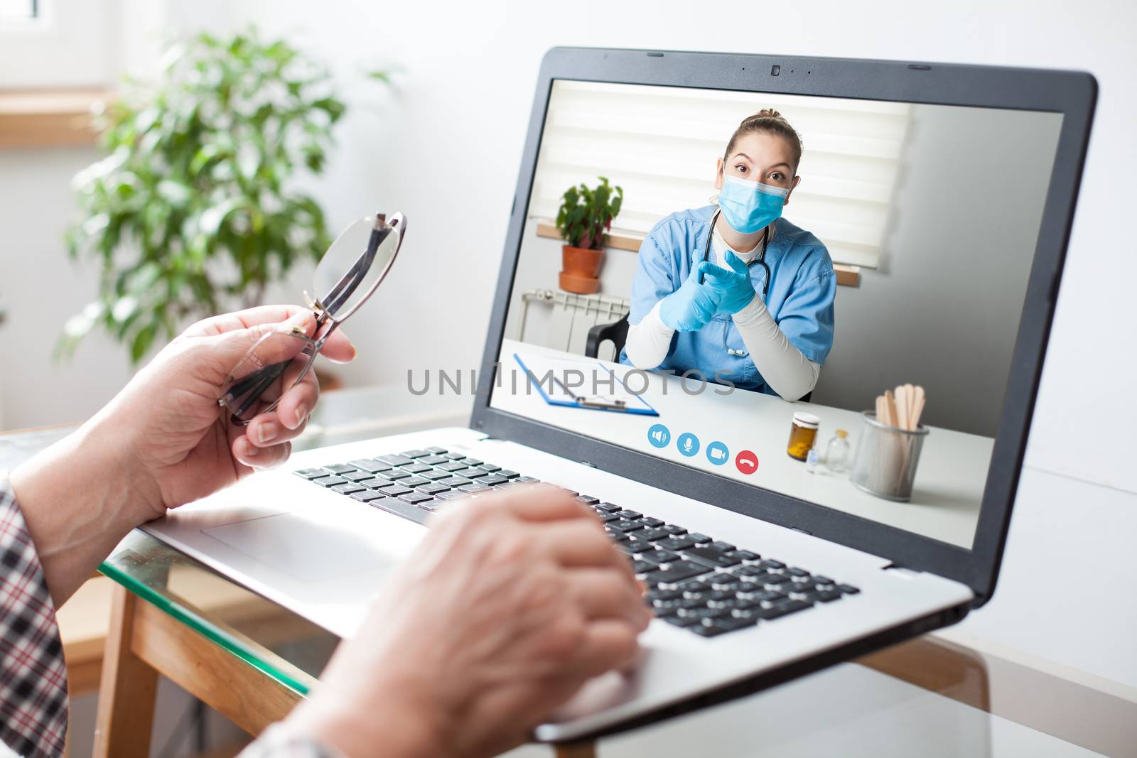Virtual doctor visit,telemedicine healthcare concept,young female doctor giving advice over laptop computer screen to elderly woman,hands holding glasses & medical worker on display,remote appointment