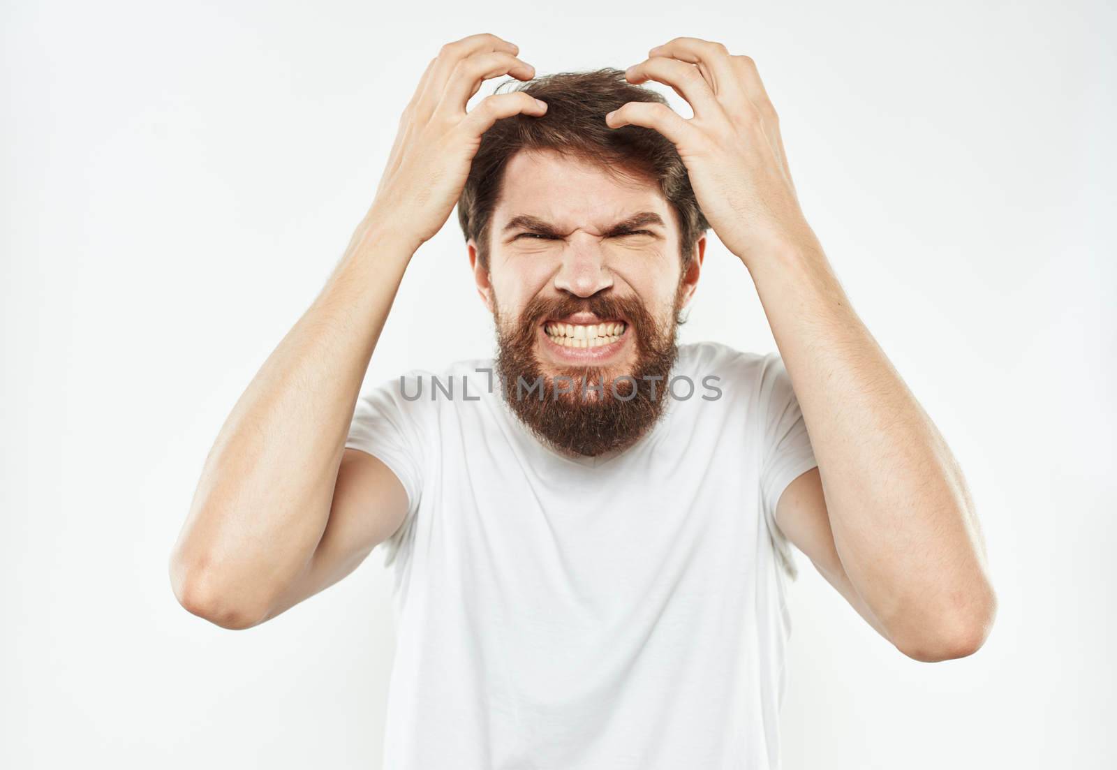 Emotional man gesticulates with his hands on a light background and a thick beard irritability. High quality photo
