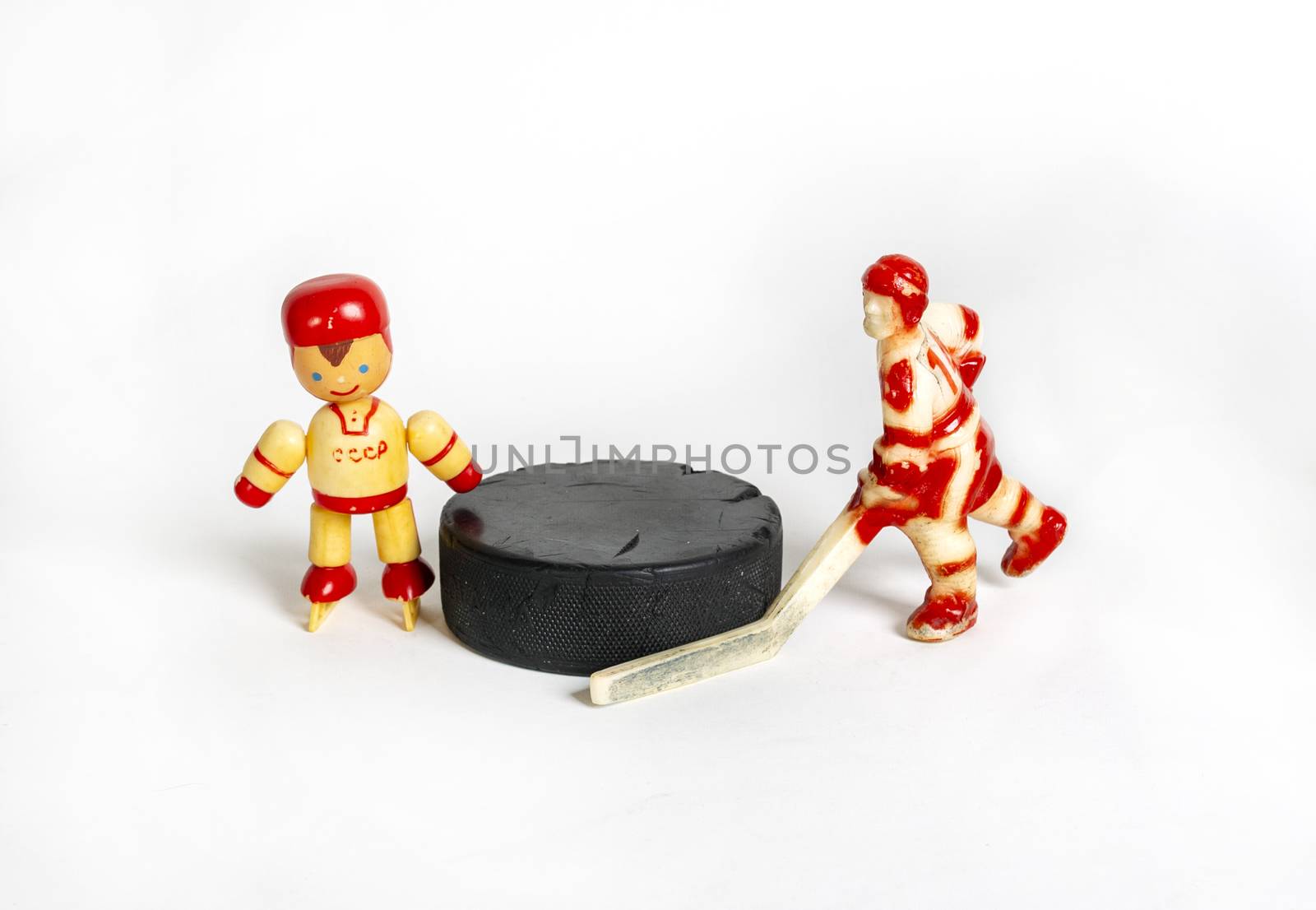 Hockey. Two red toy hockey players stand next to the puck by 977_ReX_977