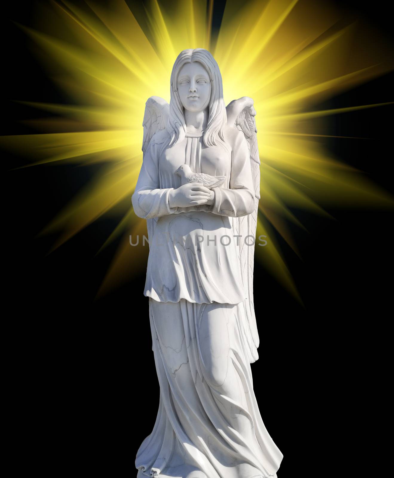 The cemetery monument in the form of an angel of white on a background of mystical light, yellow color.