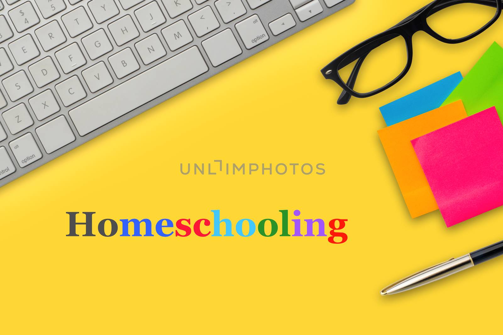 HOMESCHOOLING text with computer keyboard, eyeglasses, sticky notes and fountain pen on yellow background by silverwings