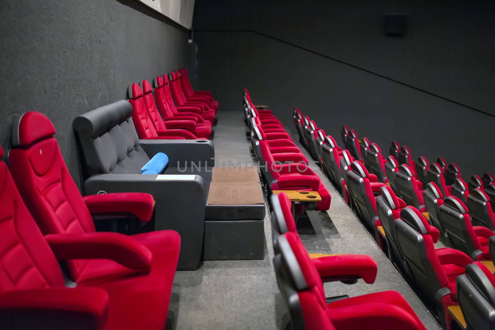 VIP chair in an empty cinema among red soft chairs.