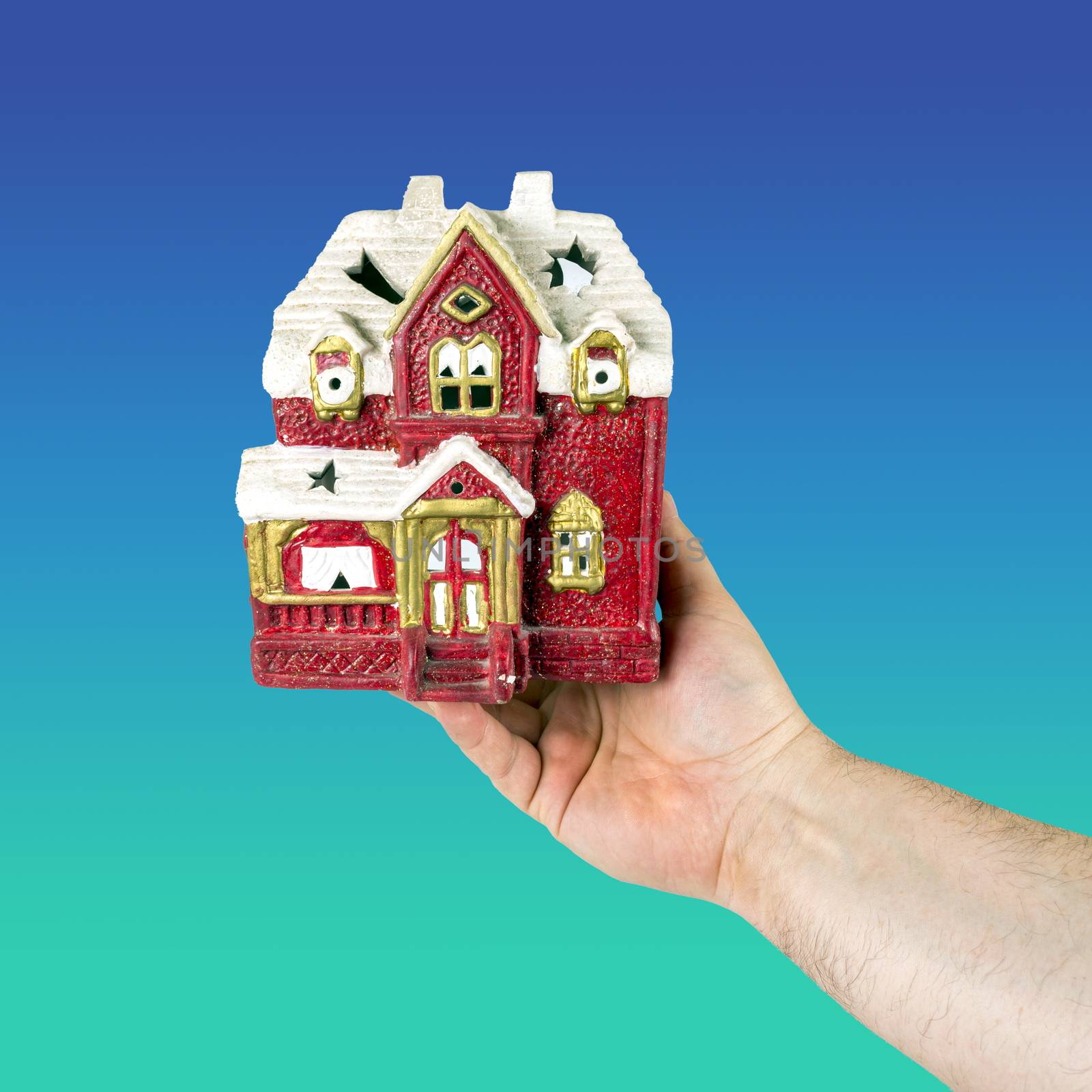 Hand holds toy house of red color. Concept of sale, purchase, rental or home insurance. Place for an inscription