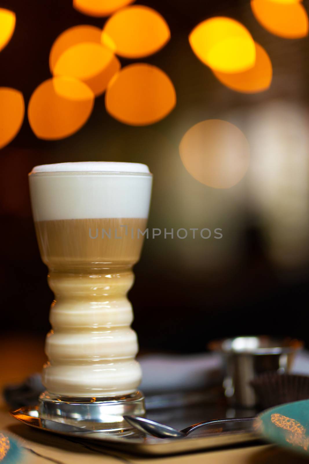 Glass cup with latte on a background of blurry bokeh lights.