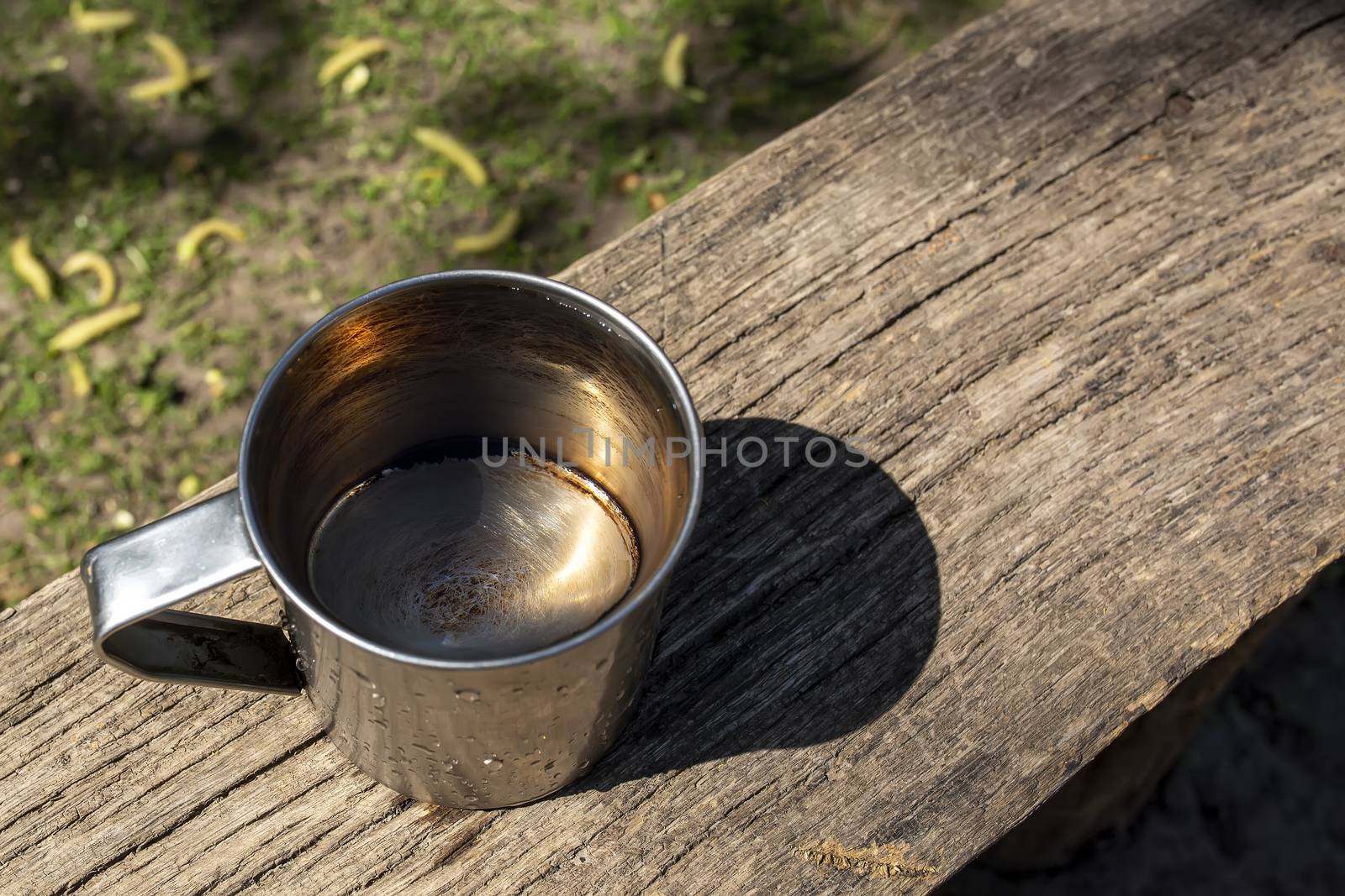 An iron mug with transparent clear water stands on a gray wooden board. Well water, environmentally friendly