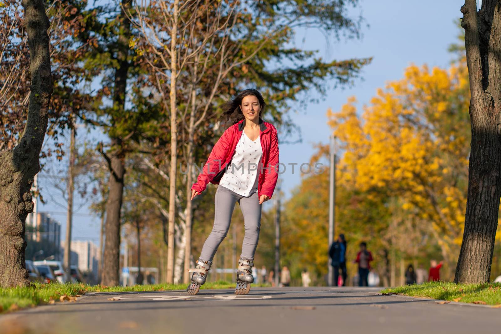 Active leisure. A sportive girl is rollerblading in an autumn park.