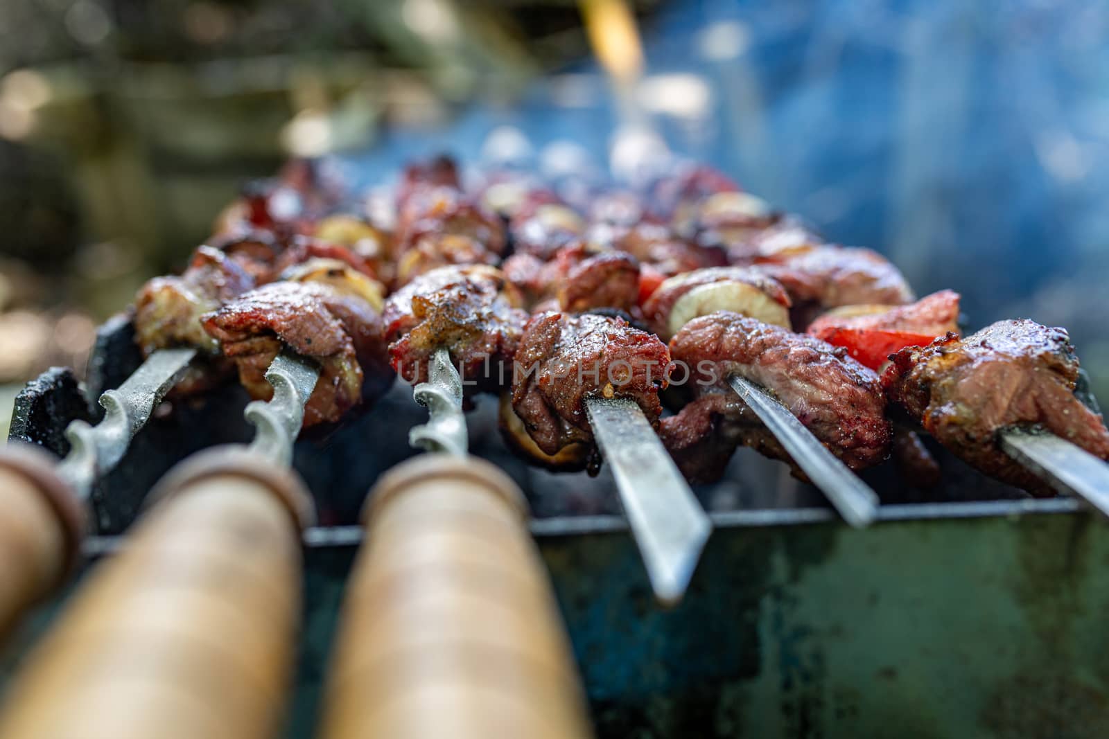 Skewers uncooked in nature on skewers in the open air. Shish kebab on the nature raw on the grill on a spit closeup. Shashlik shashlyk with onions and tomatoes