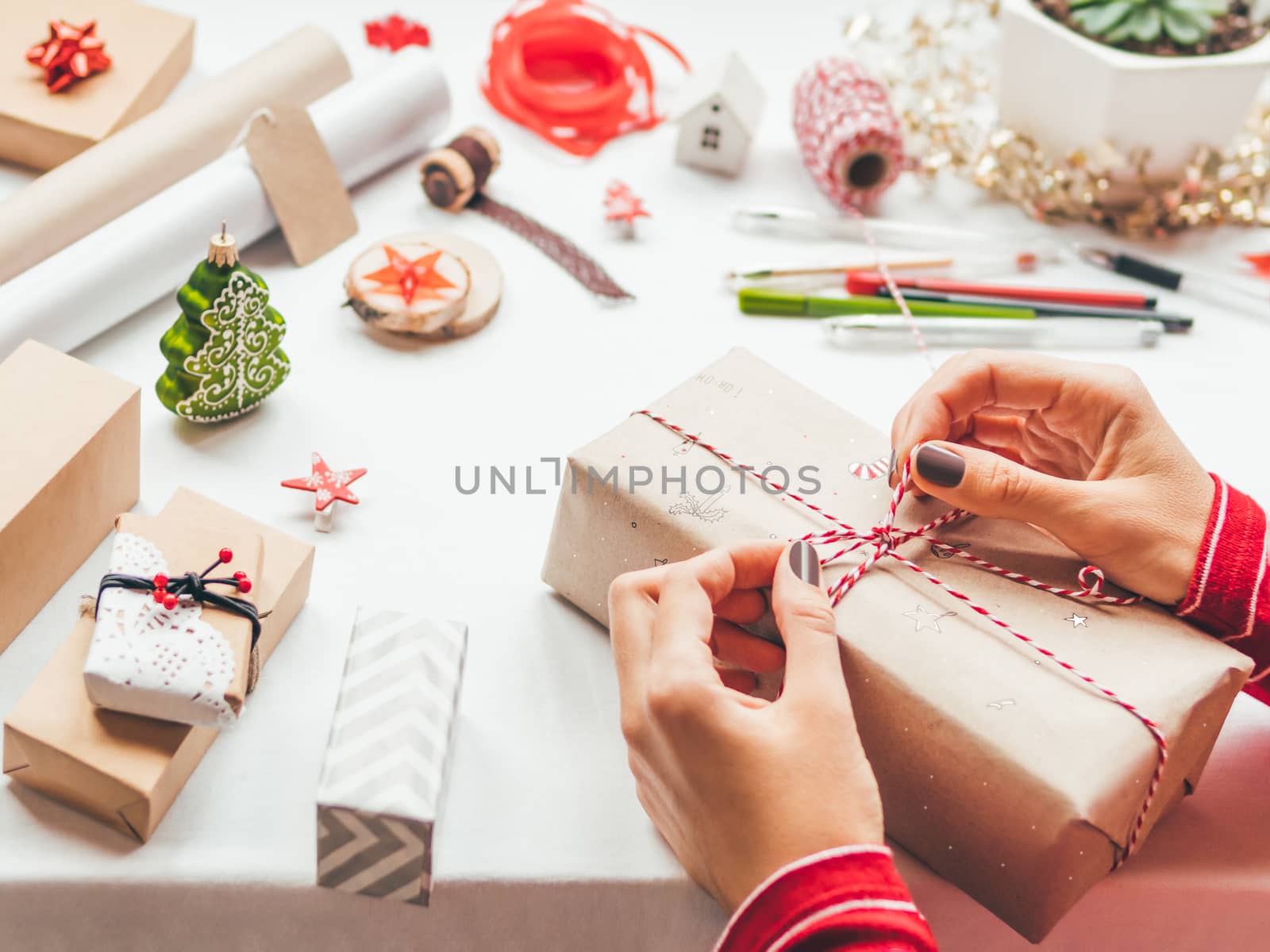 Table with Christmas decorations. Woman draws New Year symbols o by aksenovko