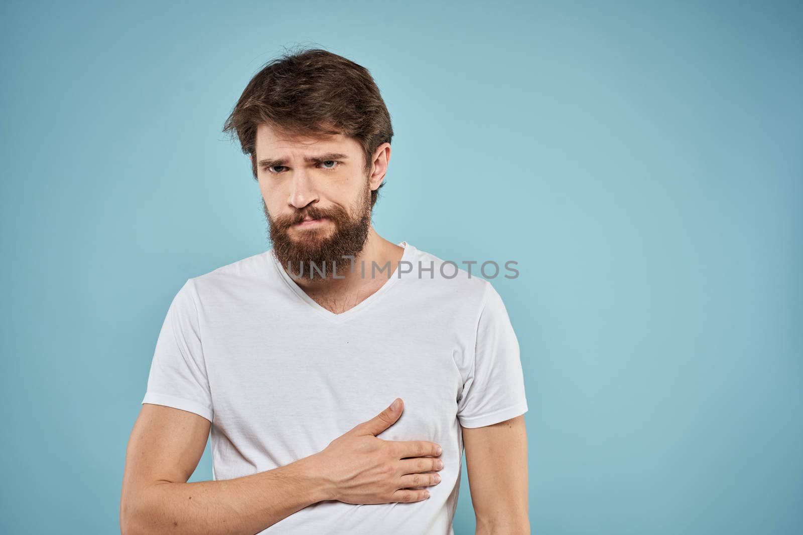 Man in white t-shirt emotions facial expression cropped view studio blue background lifestyle by SHOTPRIME