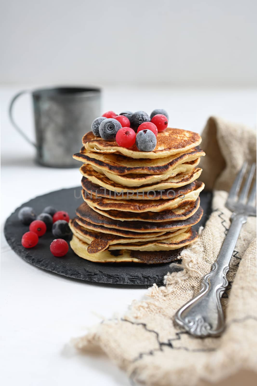 Plate with pancakes and berries on white table.