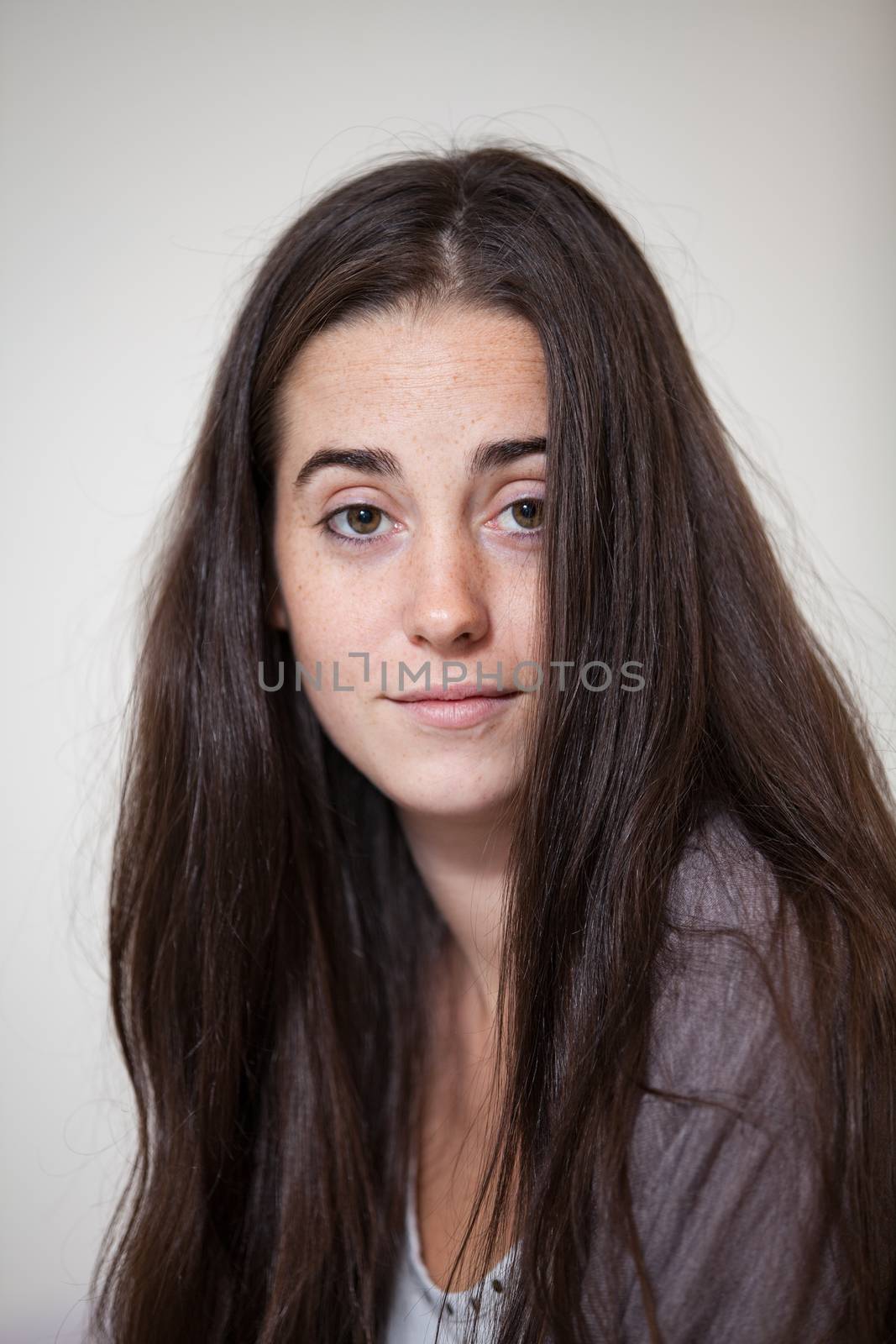 Portrait of a young and sweet natural woman without makeup with long brown hair