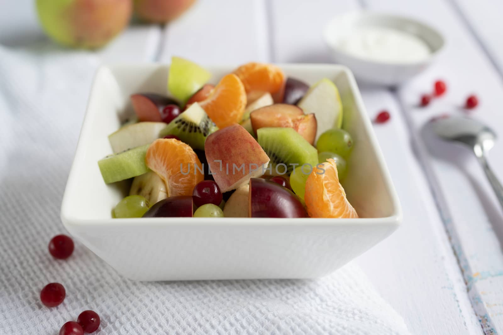 fresh fruit salad in glass bowl on white wooden background by sashokddt