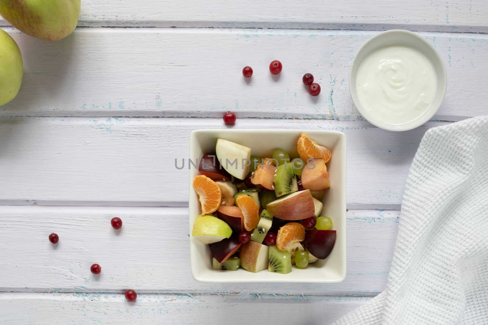 fresh fruit salad in glass bowl on white wooden background by sashokddt