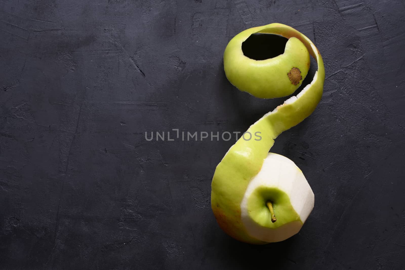Piece of cut and peeled apple, peels and seeds, on black background by sashokddt