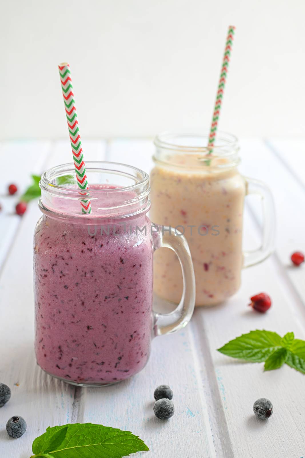 Blueberry smoothie with mint in mason jar with straw against a wood background.