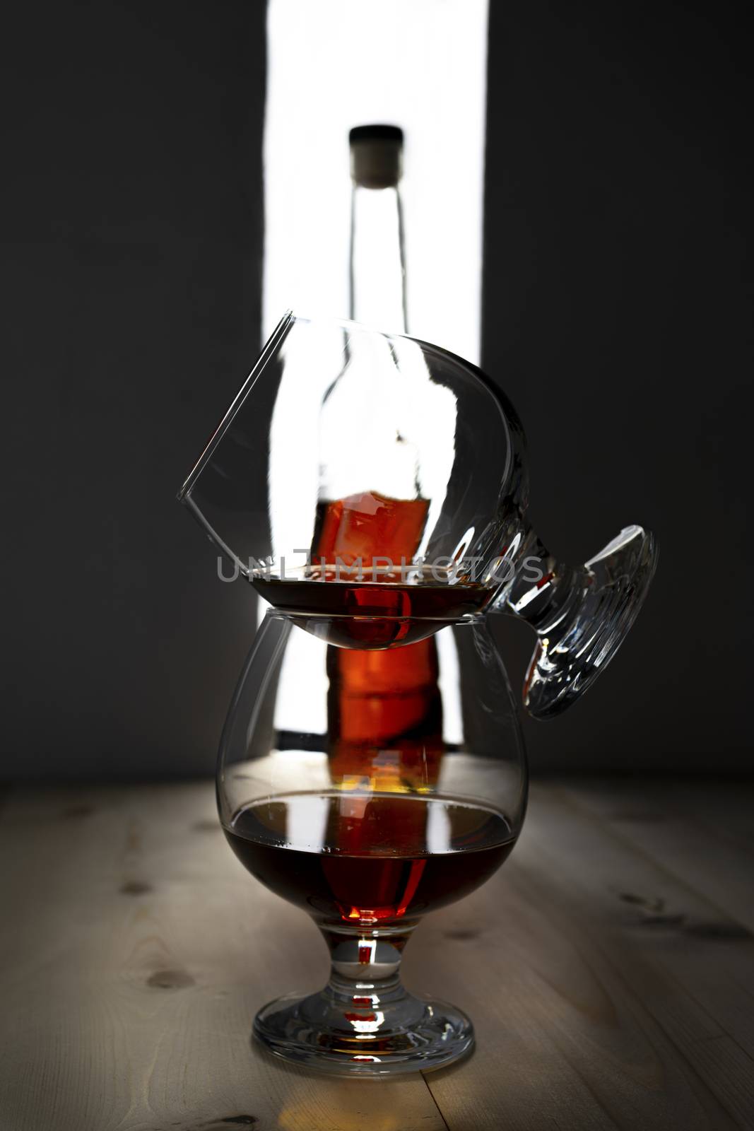 Bottle and glass of cognac over dark and white background.