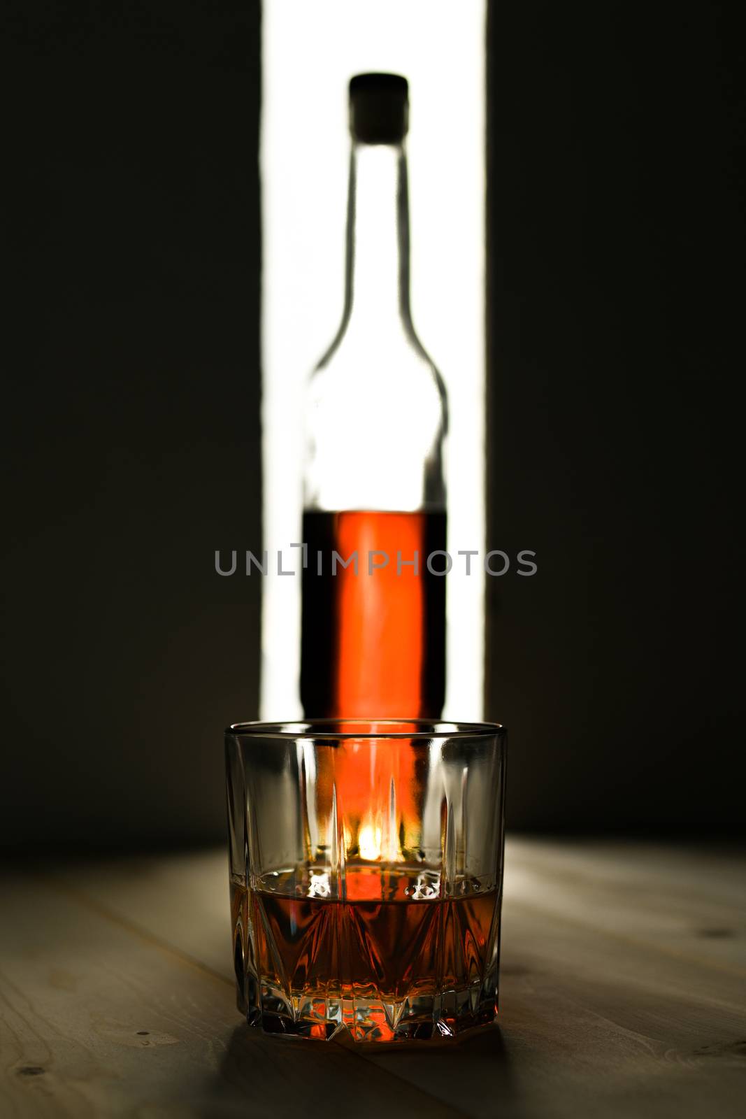 Bottle and glass of cognac over dark and white background. by sashokddt