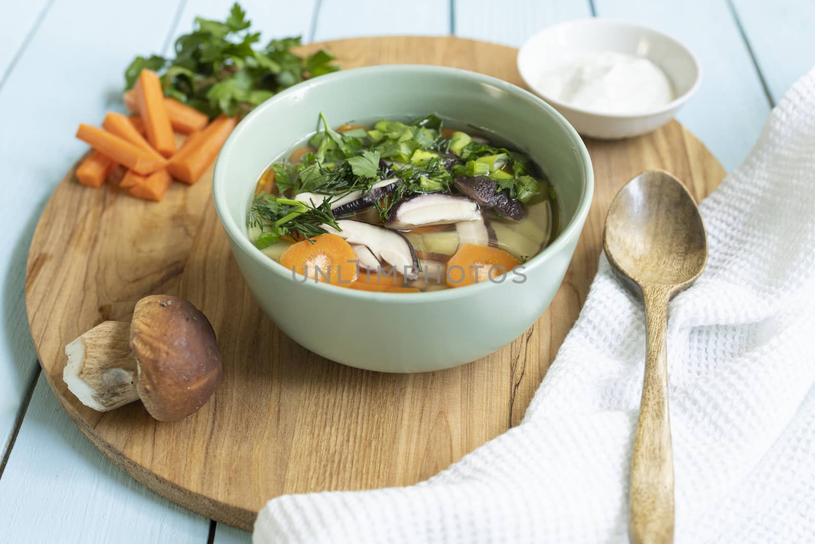 Soup with fresh white mushrooms and potato - traditional dish of russian cuisine in a clay bowl over dark wooden background.Top view with copy space