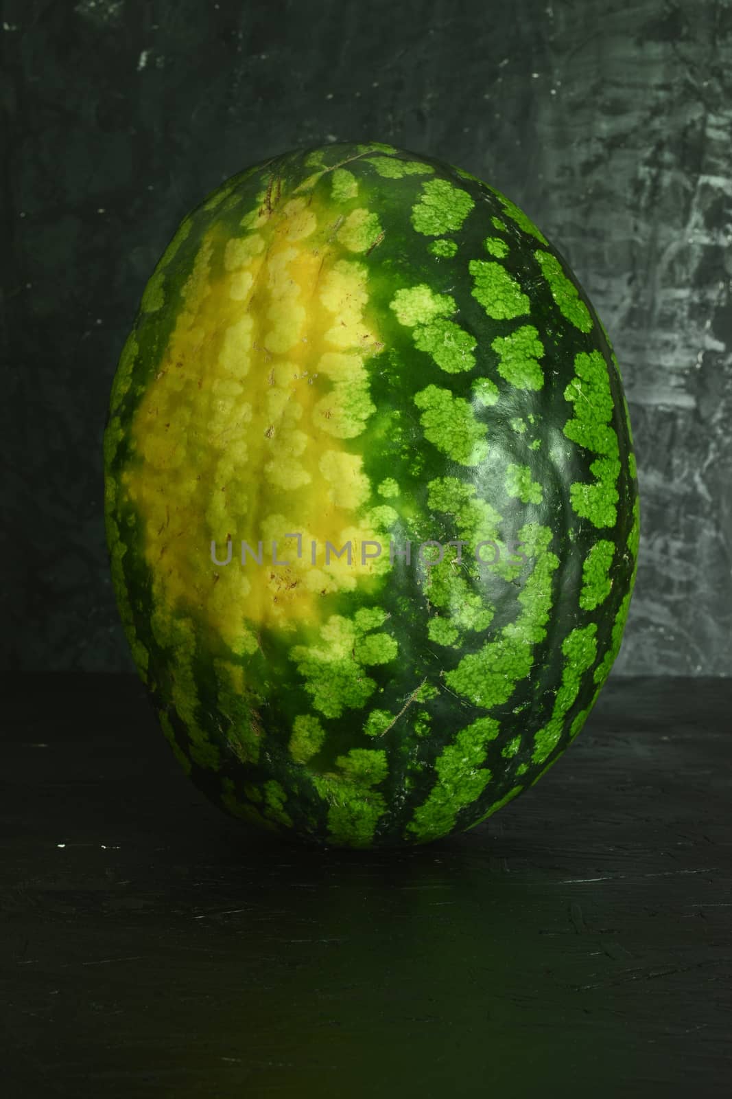 A whole big watermelon on a black table background.