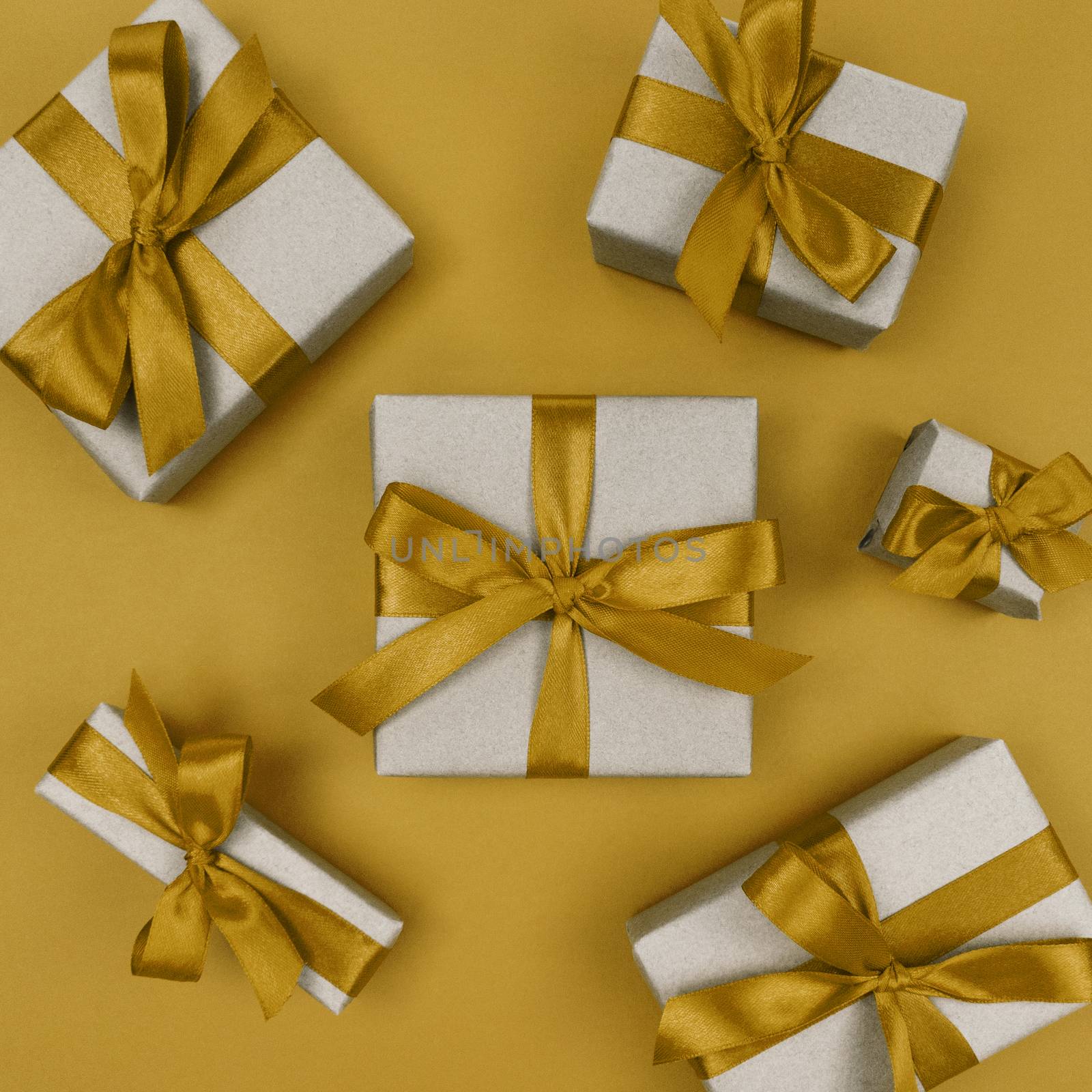 Gift boxes wrapped in a craft paper with yellow ribbons and bows. Festive monochrome flat lay.