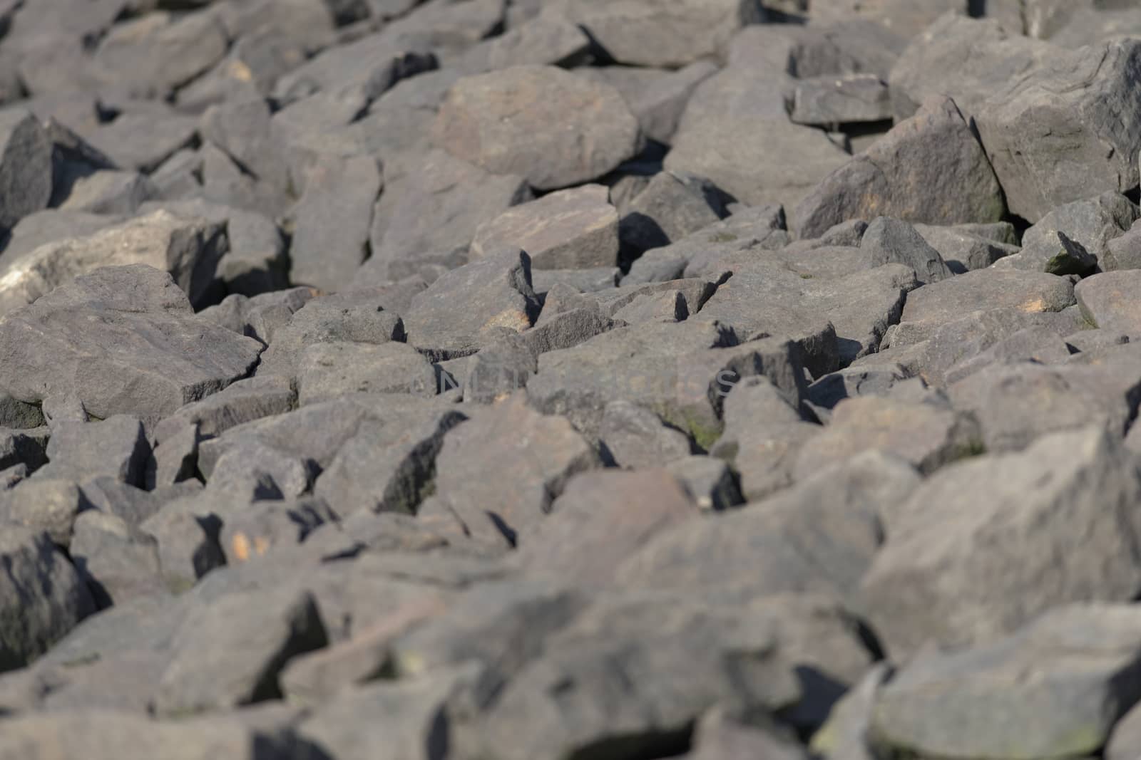 Lit by evening sunlight, A variety of sharply shaped stone boulders form a full frame abstract background texture image. Outdoors water protection