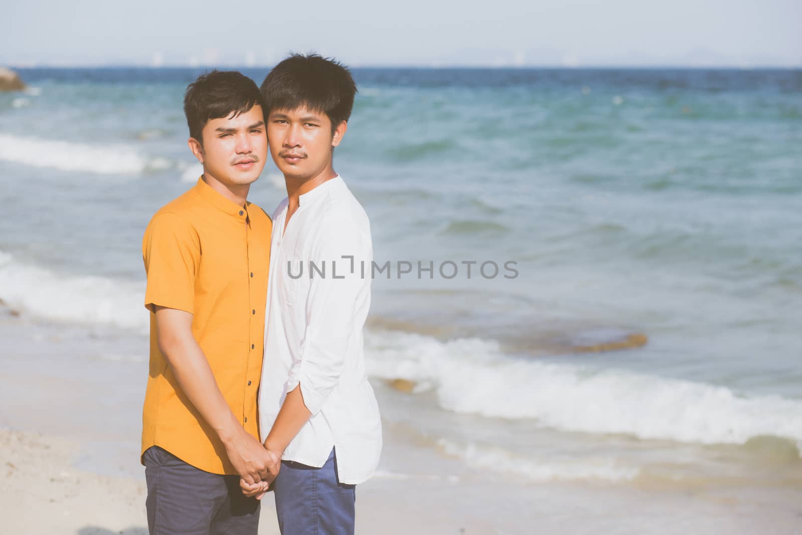 Homosexual portrait young asian couple standing together on beach in summer, asia gay holding hands going sea for leisure and relax with romantic and happy in vacation at sea, LGBT with legal concept.