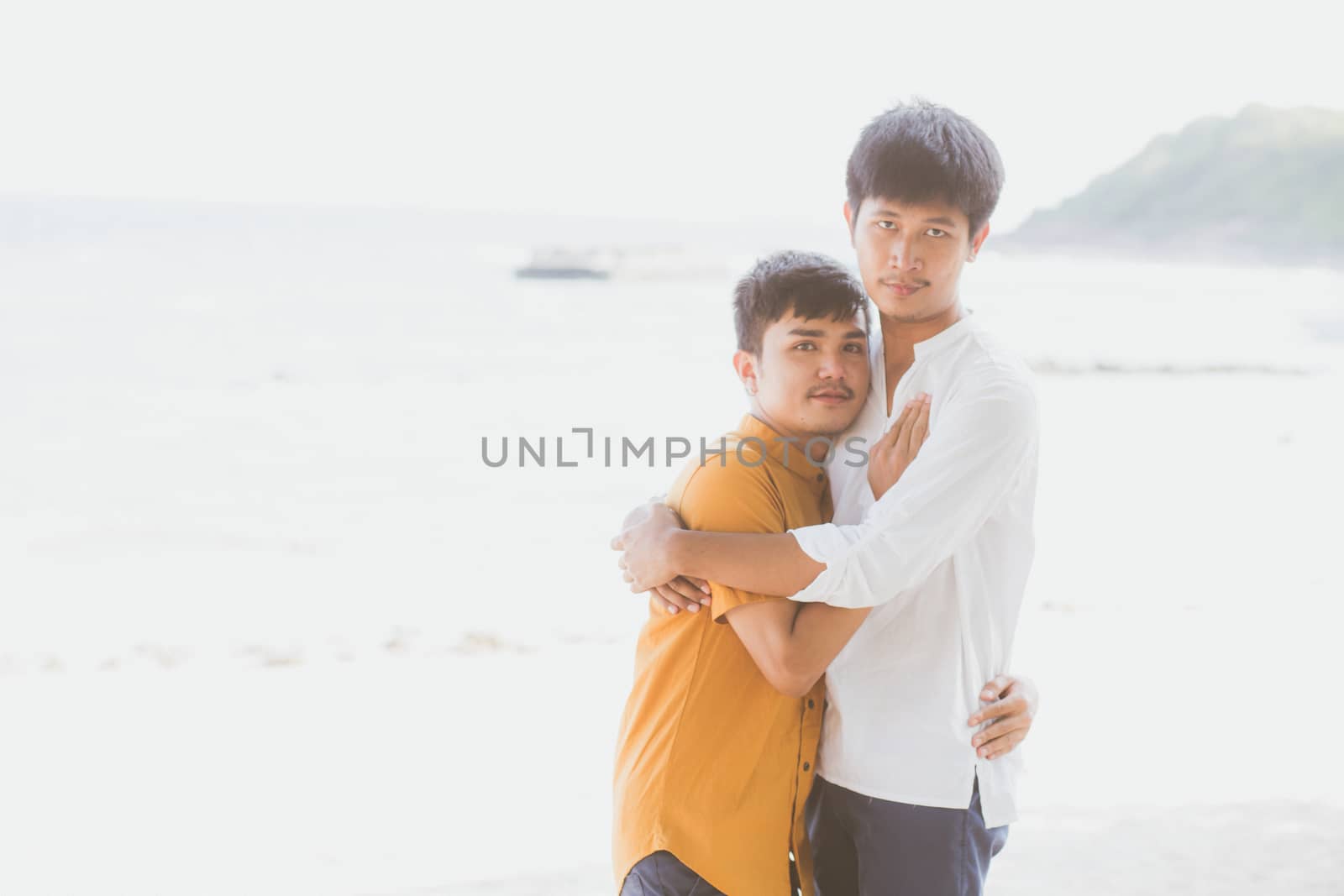 Homosexual portrait young asian couple standing hug together on beach in summer, asia gay going tourism for leisure and relax with romantic and happiness in vacation at sea, LGBT concept.