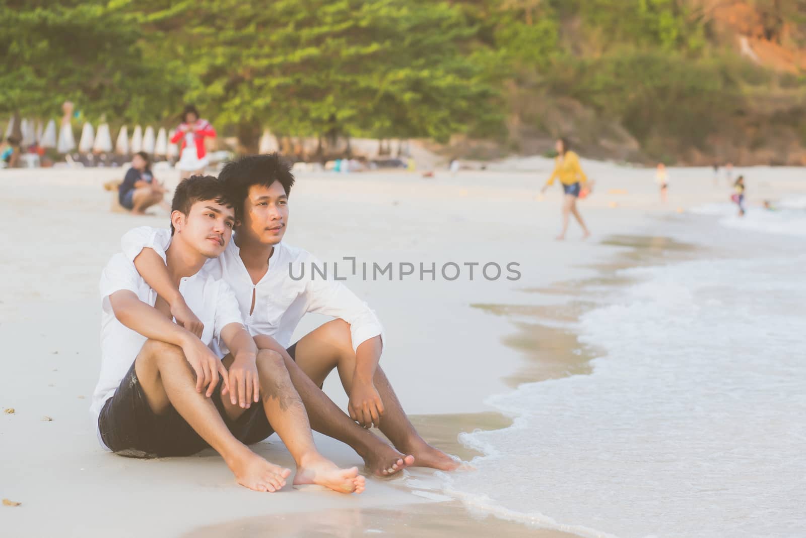 Homosexual portrait young asian couple sitting hug together on beach in summer, asia gay going tourism for leisure and relax with romantic and happiness in vacation at sea, LGBT legal concept.