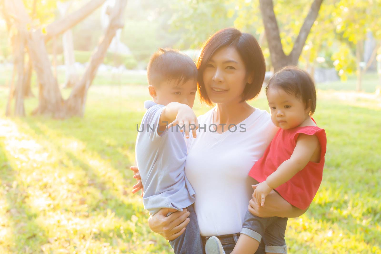Beautiful young asian mother carrying little boy and girl in the by nnudoo