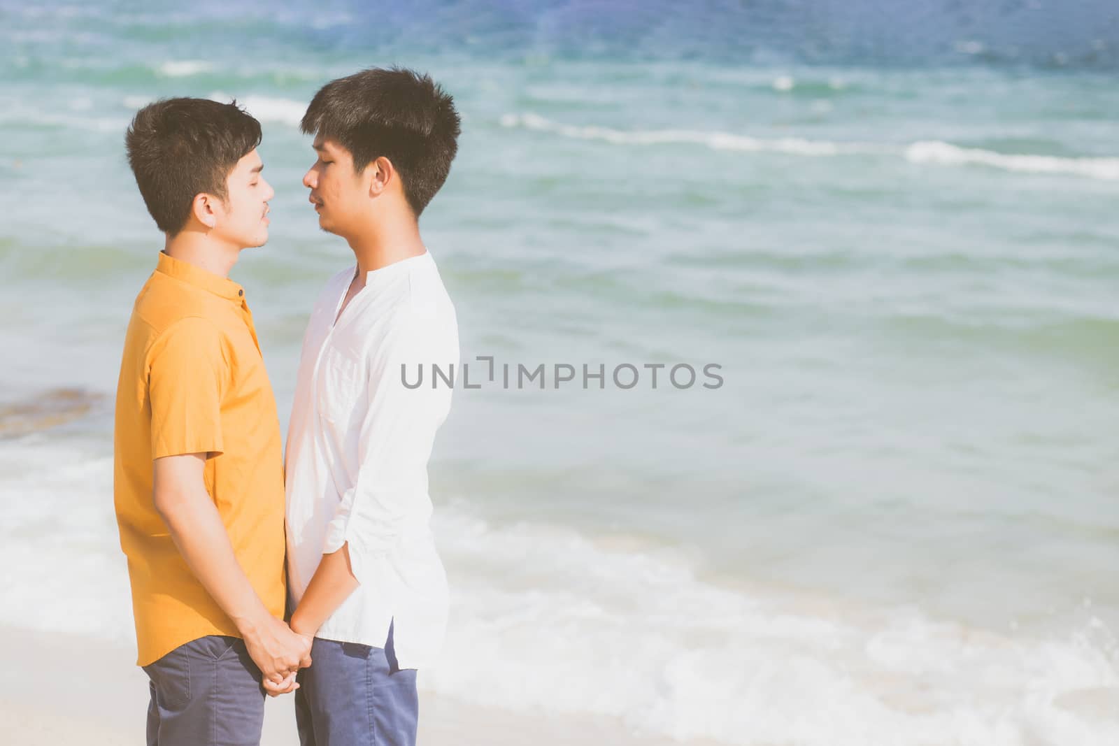 Homosexual portrait young asian couple standing together on beach in summer, asia gay holding hands going sea for leisure and relax with romantic and happy in vacation at sea, LGBT with legal concept.