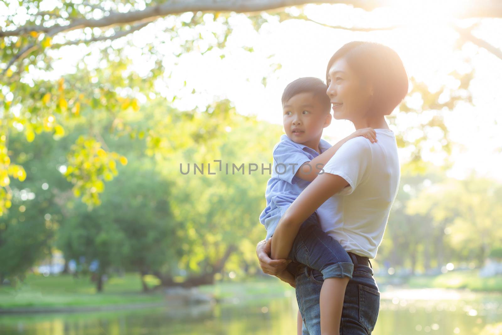 Beautiful young asian mother carrying little boy in the park, as by nnudoo