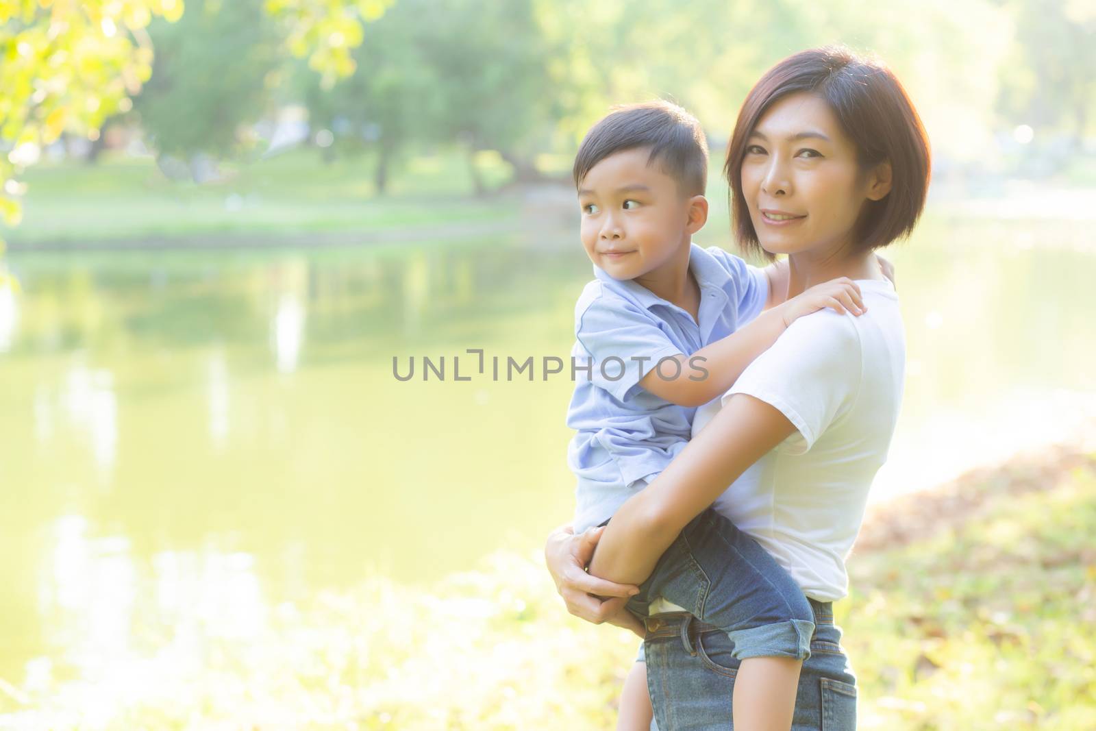 Beautiful young asian mother carrying little boy in the park, asia woman happy having son and hug kid, mom love and embracing child together in summer, mother day and family concept.